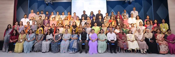 Large group photo of about 70 men and women posed in rows in an auditorium, with a projected screen behind them. - Bhavan's BVM Ashti