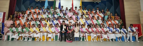 Bhavan's BVM Ashti students in white uniforms wearing colored sashes, posed on stage during Investiture Ceremony
