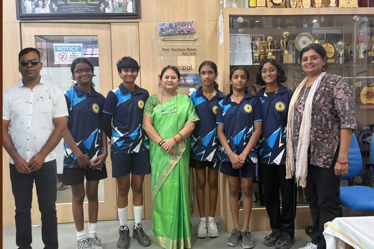 Group photo of five students in matching blue sports uniforms standing with three adults in front of a trophy display cabinet in an office. - Bhavan's BVM Ashti
