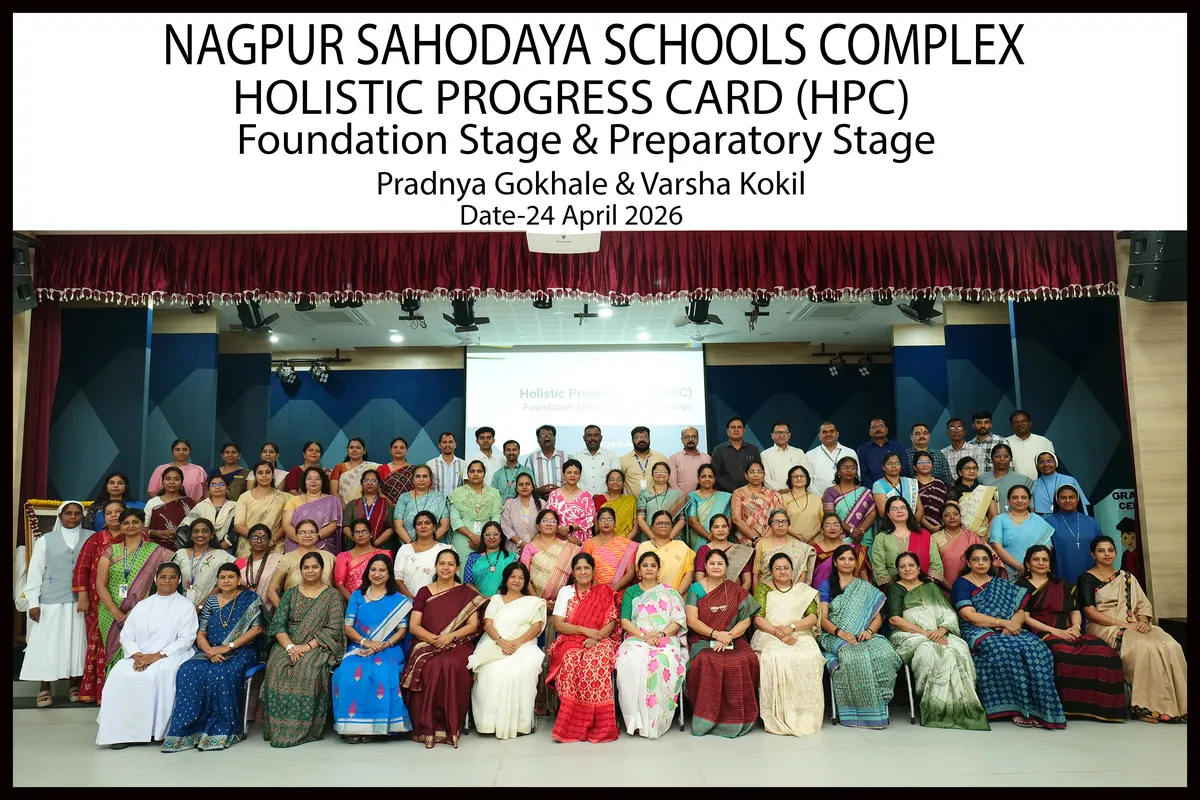 Large group photo of about 60 teachers and staff posed in rows on an auditorium stage with a heading banner above in English. - Bhavan's BVM Ashti