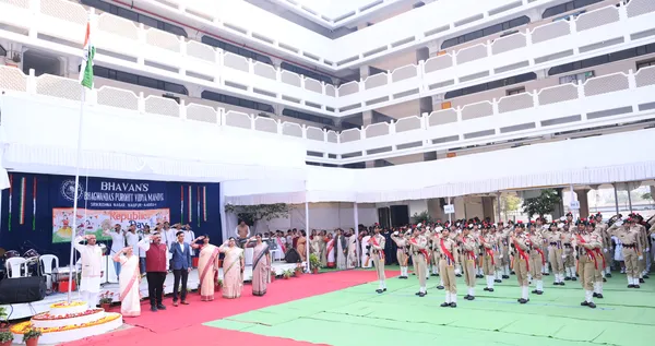 Flag hoisting ceremony in a school courtyard with uniformed cadets in formation and guests standing beside a decorated banner at Bhavan's BVM SKN