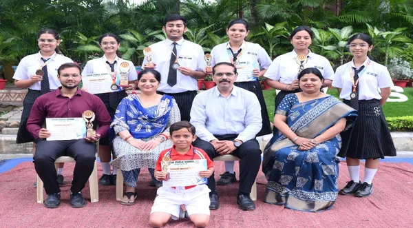 Cropped, wider version of a group photo of students and adults holding trophies, medals and certificates outdoors. - Bhavan's BVM SKN