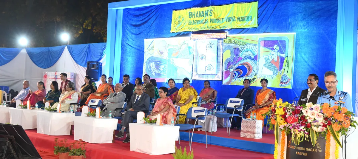 Guests seated on a decorated stage with floral arrangement and banner at Bhavan's BVM SKN event