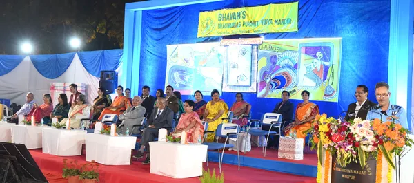 Guests seated on a decorated stage with floral arrangement and banner at Bhavan's BVM SKN event