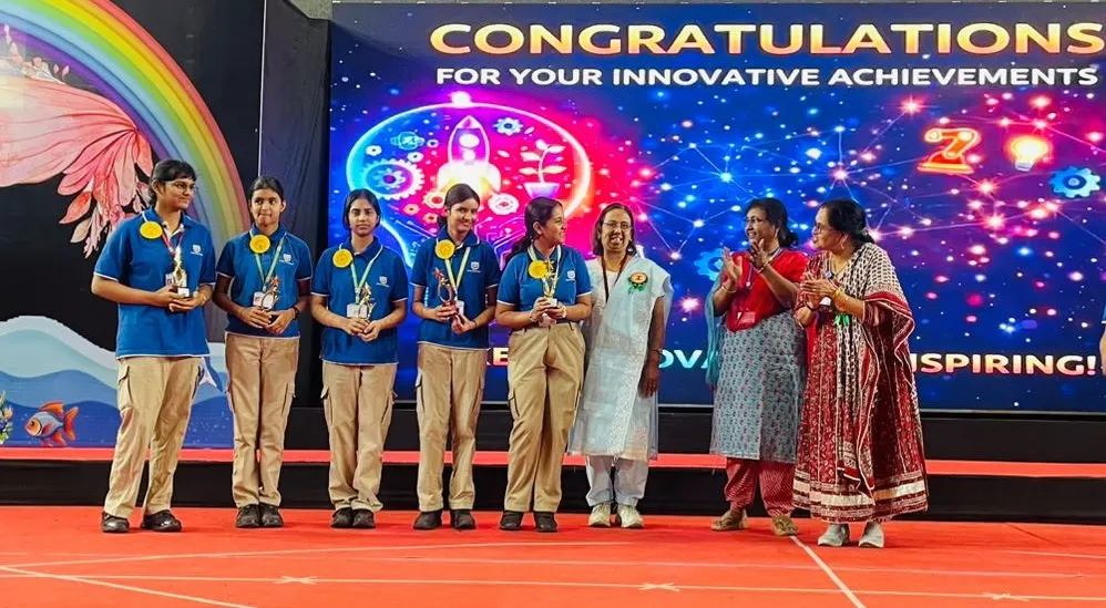 Students in blue uniforms with medals and trophies stand on stage at the Cennovation Program, CPS (Katol Road)