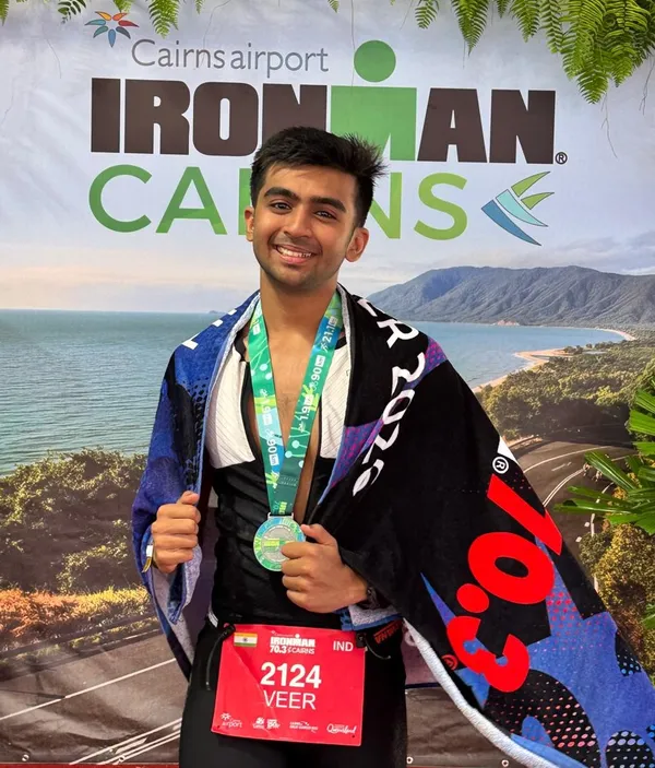 CPS (Katol Road) alumnus Veer Rajwade wearing a finisher medal and race bib in front of a triathlon event backdrop