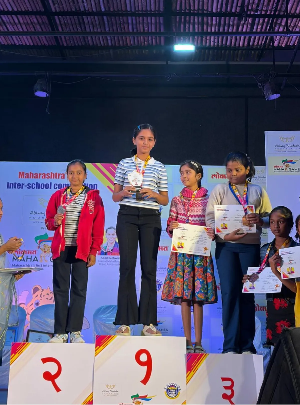 CPS (Wardhaman Nagar) students with medals, trophy and certificates on prize podium at inter-school chess competition