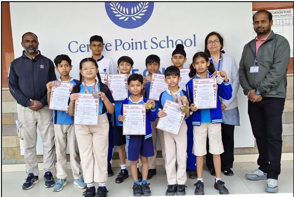 Group photo of several students in uniform holding certificates and medals, standing with three adults in front of CPS (Wardhaman Nagar) school wall sign.