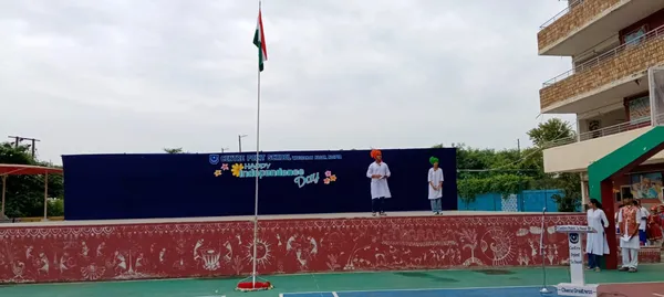 Two CPS (Wardhaman Nagar) students on a stage with flagpole and Independence Day backdrop