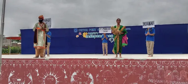 CPS (Wardhaman Nagar) students in historical costume on a stage holding name placards in front of Independence Day banner
