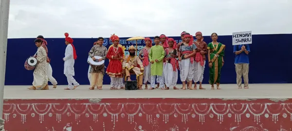 Group of CPS (Wardhaman Nagar) students in traditional costumes with drums and umbrella performing on stage