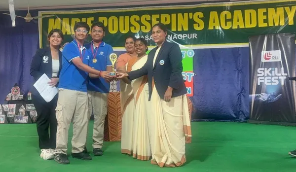 Two students in blue shirts receive a trophy on a stage with a banner and a Skill Fest standee behind them.