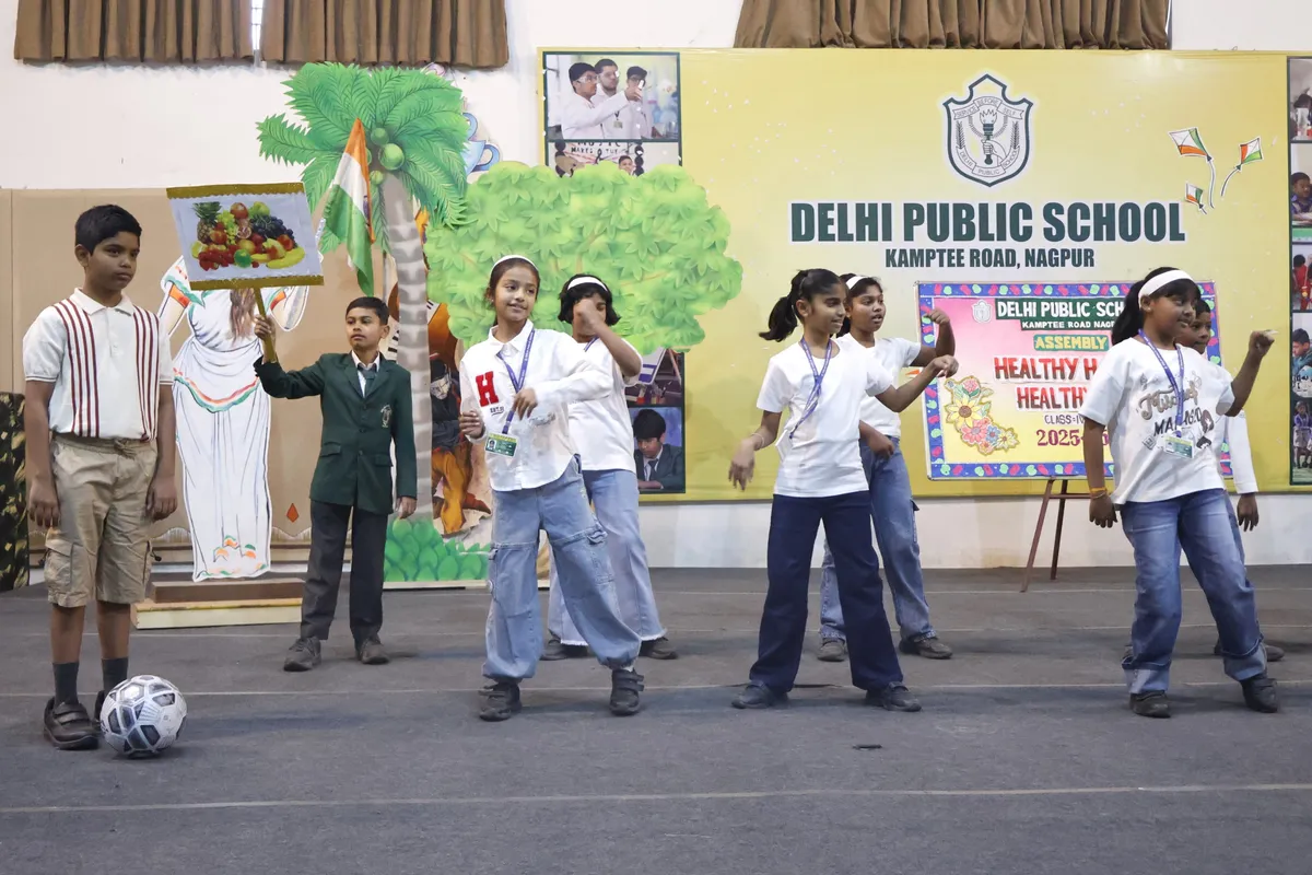 DPS (Kamptee Road) students performing on stage during assembly in front of a decorated backdrop
