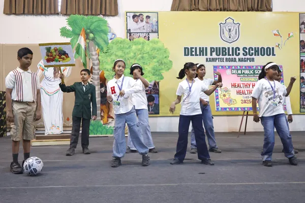 DPS (Kamptee Road) students performing on stage during assembly in front of a decorated backdrop