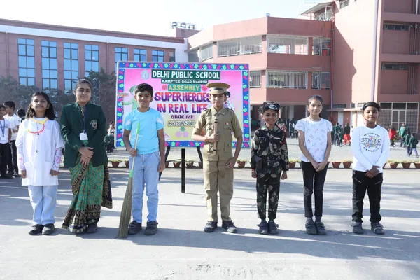 Seven students in costumes including doctor, policeman and soldier standing in a row beside an assembly signboard in a school courtyard at DPS (Kamptee Road)