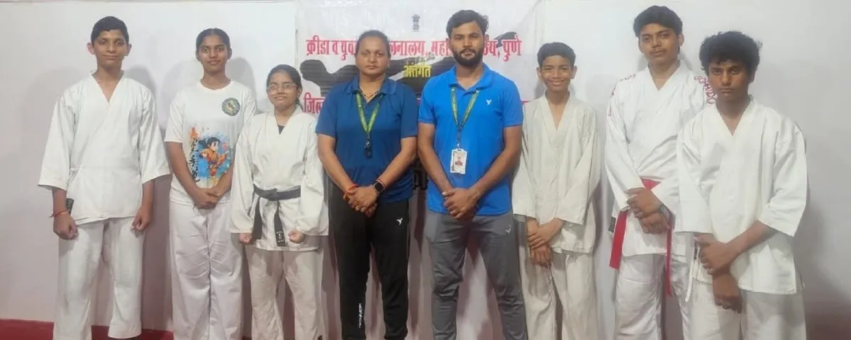 group photo of six students in white martial arts uniforms with two adults in blue shirts standing in front of a banner - DPS (Kamptee Road)