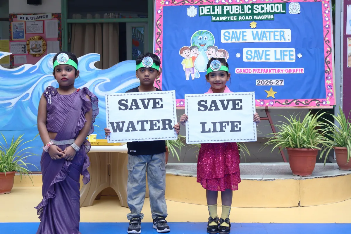 Students at a school activity wearing headbands, holding signs in front of a decorated board, DPS (Kamptee Road)