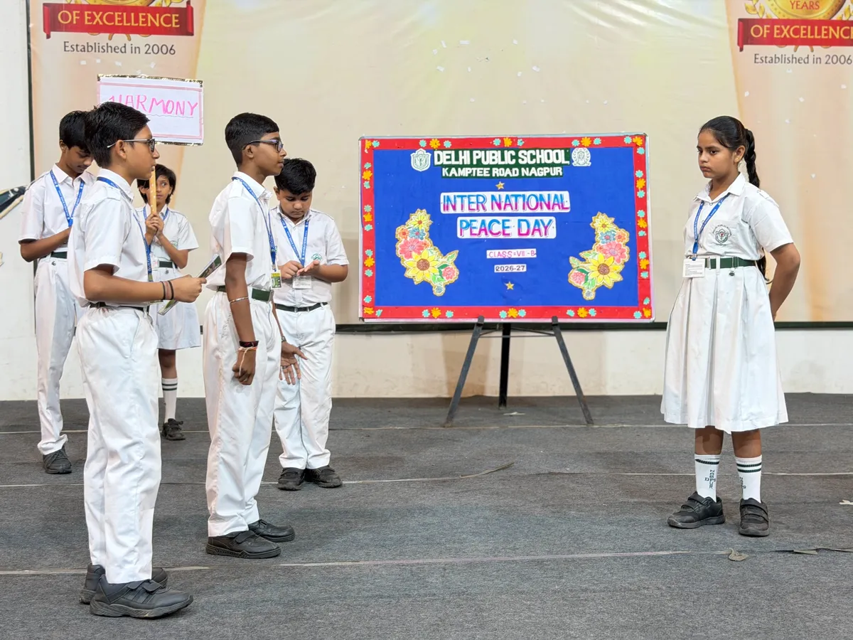 Students in white school uniforms performing on a stage for an International Peace Day event at DPS (Kamptee Road)