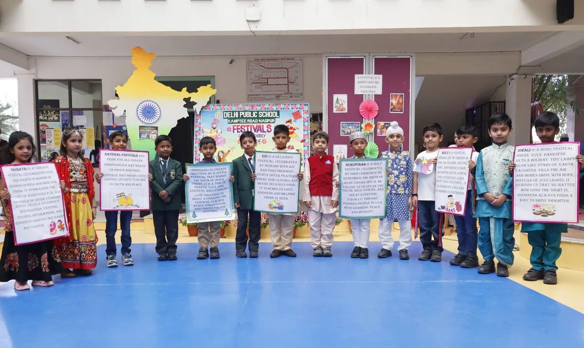 Group of Grade I students in festival costumes holding placards about festivals in front of a festivals display board and map of India, DPS (Kamptee Road)