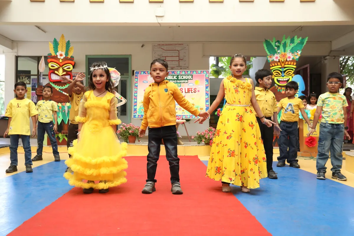Young children in yellow costumes performing on a stage with colorful decorations at DPS (Kamptee Road)