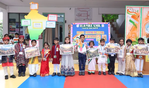 Group of young students in traditional dress holding regional pictures in front of a map of India and a school activity banner. - DPS (Kamptee Road)