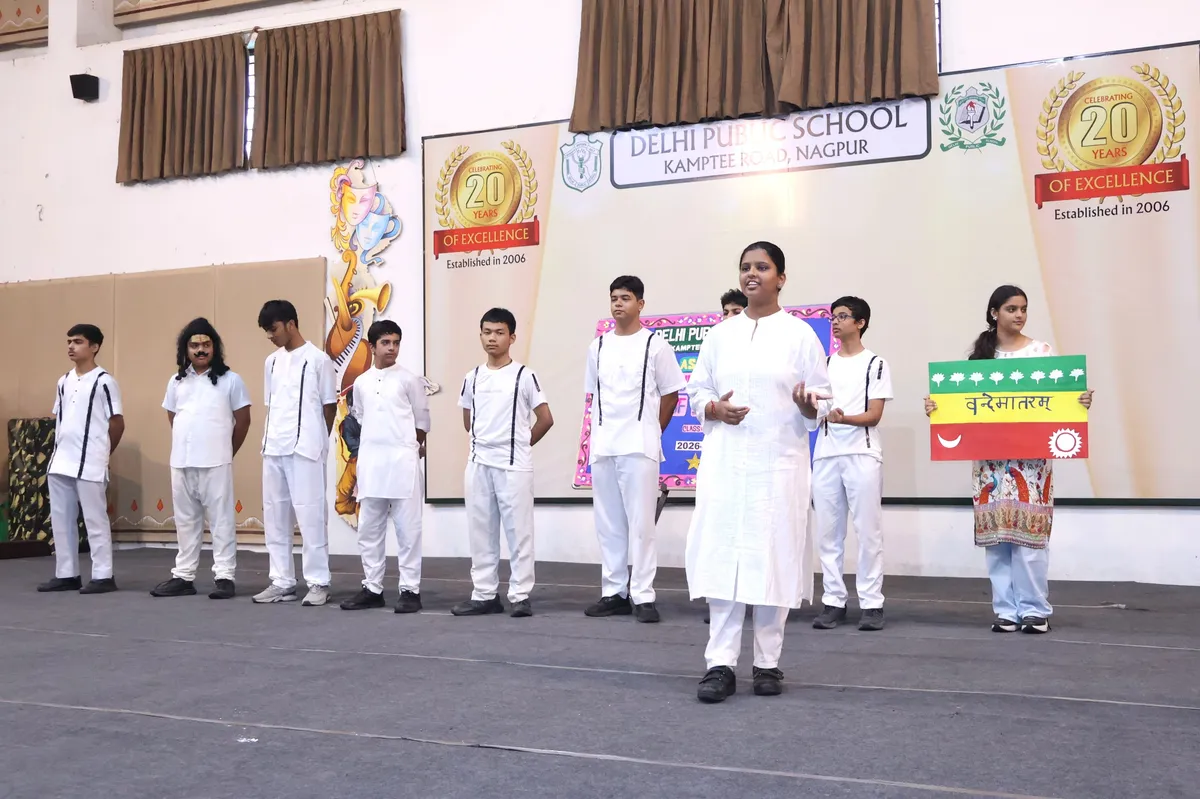 Students and a teacher on stage at DPS (Kamptee Road) assembly, one student holding a colored board.