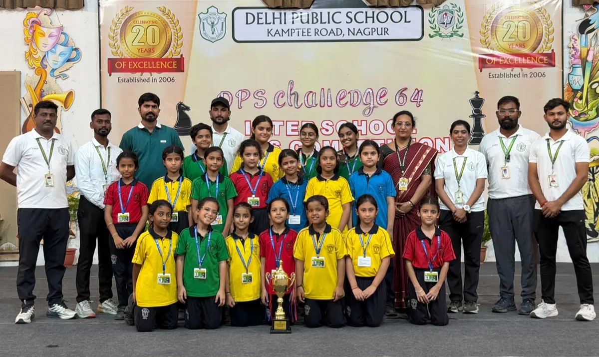 Group photo of students in school uniforms and staff on stage with trophy and school banner at DPS (Kamptee Road)