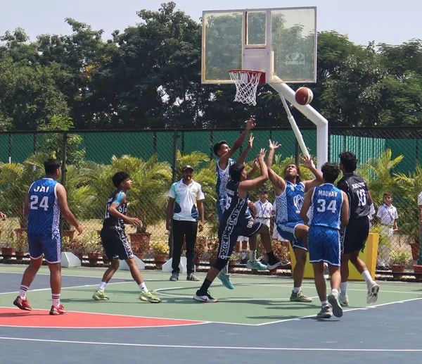 Players in blue and black jerseys jump for the ball under the basket during a match at DPS (Mihan).
