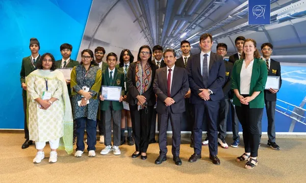 Group photo of students and adults, some holding certificates, posed in front of a large backdrop with a logo