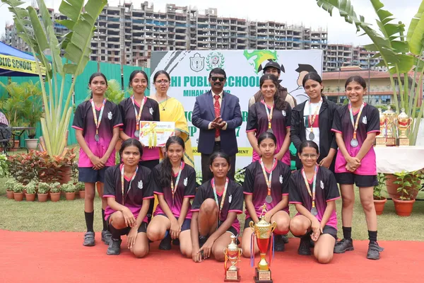 Group photo of girls in dark pink and black jerseys with medals, trophies and certificate at DPS (Mihan)