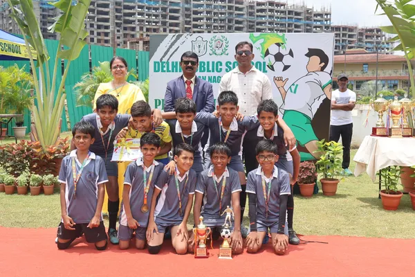 Group photo of young boys in grey jerseys with trophies and football at DPS (Mihan)