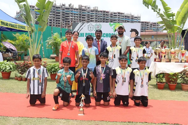 Group photo of boys in mixed jerseys wearing medals with trophy at DPS (Mihan)