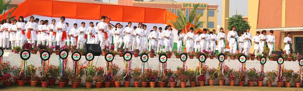 Students in white outfits standing in rows behind a flower-decorated platform at DPS (Mihan)