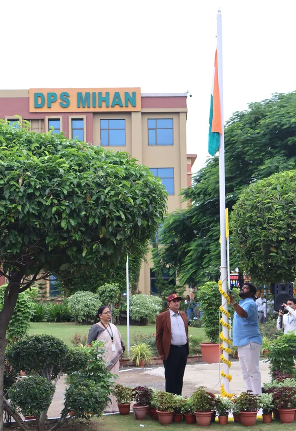 A man hoists the Indian flag on a pole while a woman and another man stand nearby in front of a school building. - DPS (Mihan)