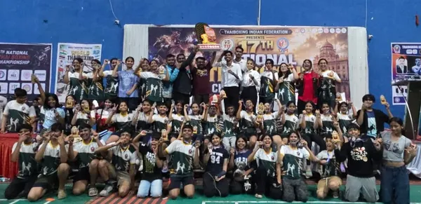 Group photo of young athletes in matching jerseys holding medals and a trophy in front of a championship banner at DPS (Mihan).
