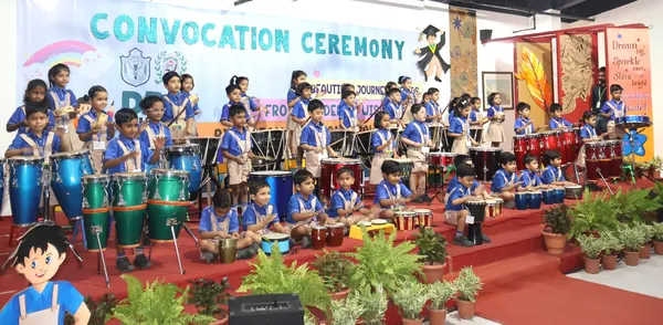 Young students in blue uniforms playing drums on stage at DPS (Mihan) convocation ceremony.