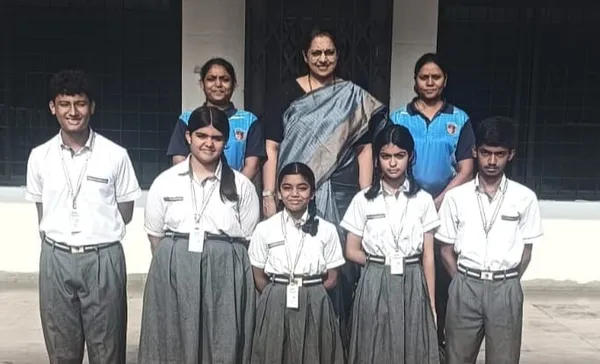 Group photo of five students in school uniforms standing in front of three women teachers outdoors against a building wall. - Narayana Vidyalayam