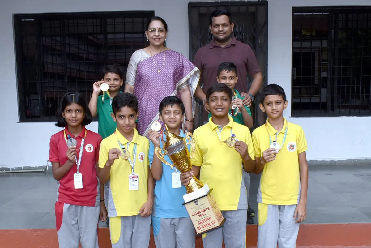 Group photo of six students and two adults posing with medals and a large trophy in front of Narayana Vidyalayam.