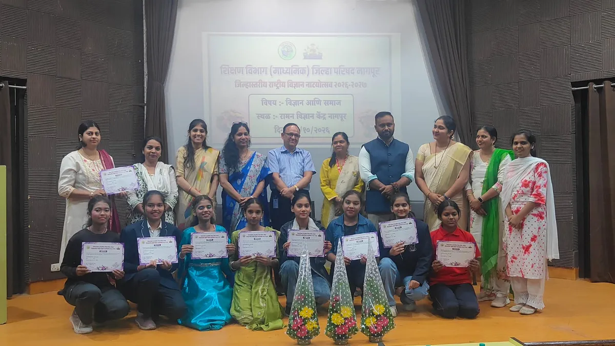 Group photo of students holding certificates, kneeling in front of standing adults, on a stage with a banner behind them. - St. Ursula
