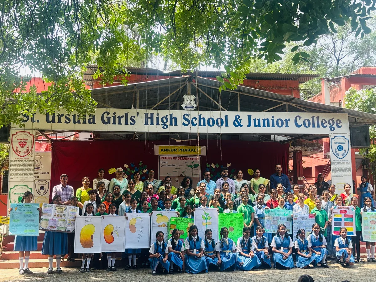 St. Ursula schoolgirls and teachers on stage holding charts and posters about seed germination.