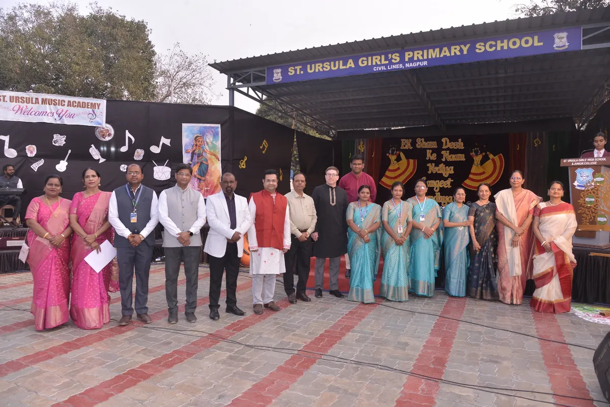 Group photo of attendees on stage at St. Ursula Girls' High School and Junior College with music-themed decorations behind them.
