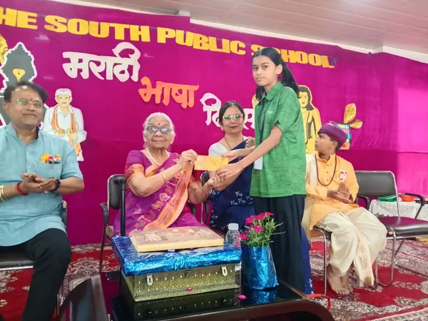 The South Public School event: girl in green shirt and elderly woman on stage with others nearby.