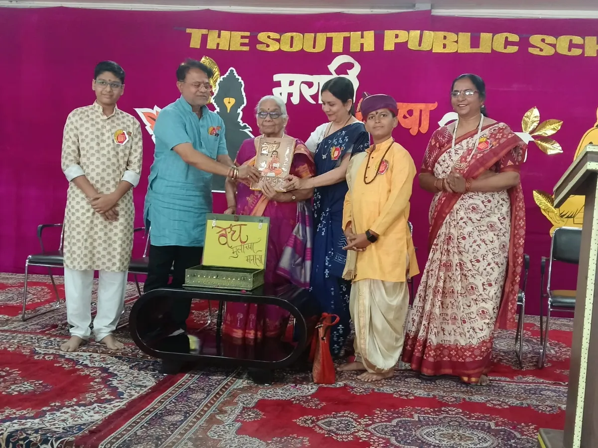 The South Public School event: students in traditional dress and guest on stage with magenta school backdrop.