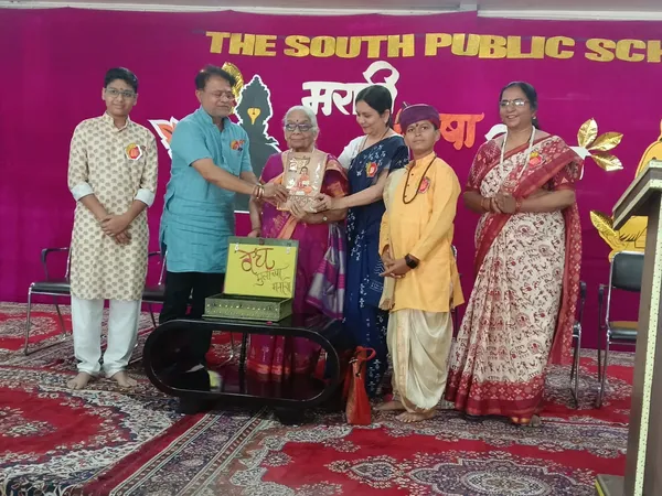 The South Public School event: students in traditional dress and guest on stage with magenta school backdrop.